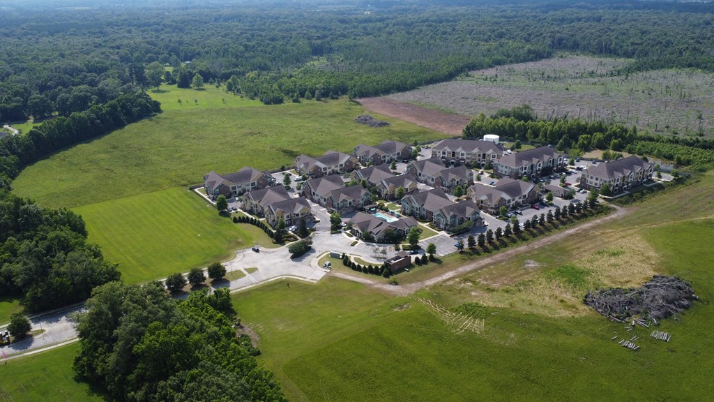 an aerial view of a large suburban neighborhood with a field and trees at Audubon Park Apartment Homes, Louisiana