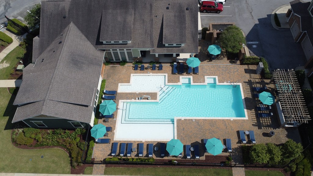 an aerial view of a swimming pool with blue tables and umbrellas around it at Audubon Park Apartment Homes, Louisiana, 70791