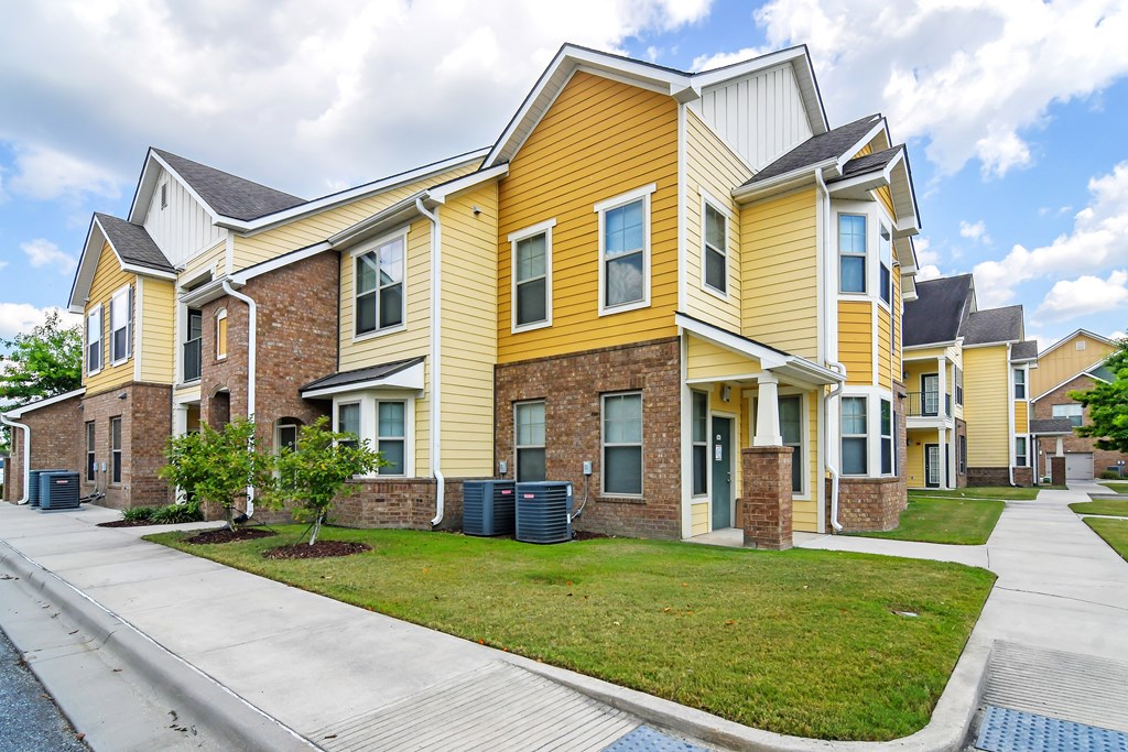 a row of yellow houses with a sidewalk in front of them at Audubon Park Apartment Homes, Louisiana