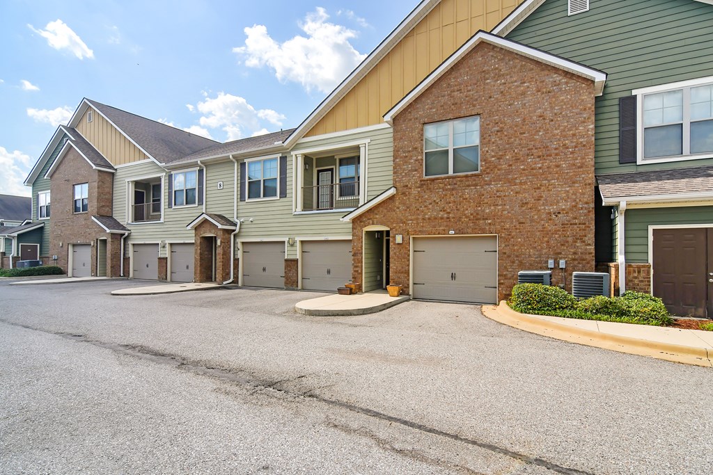 an empty driveway in front of a brick house with garages at Audubon Park Apartment Homes, Zachary