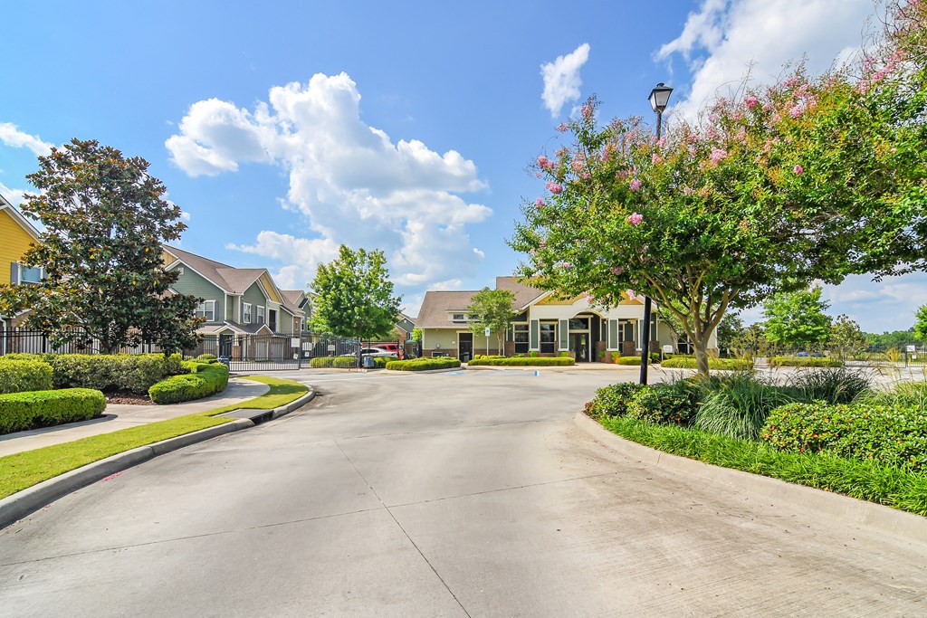 an empty street in a neighborhood with houses and trees at Audubon Park Apartment Homes, Zachary, 70791