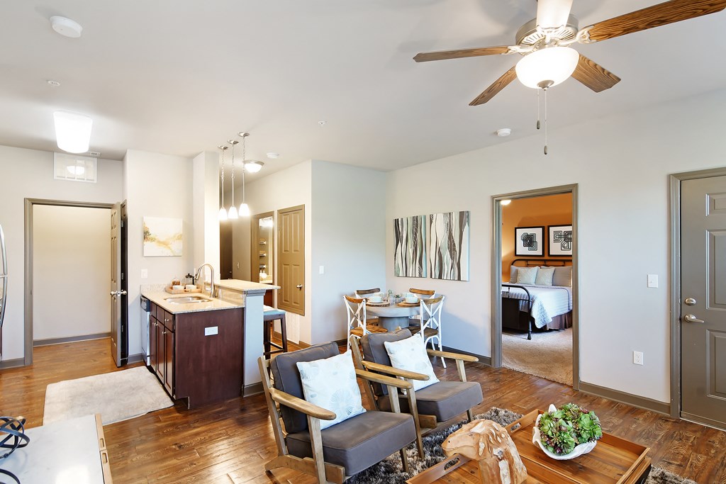 a living room with a dining room and a kitchen with a table and chairs at Audubon Park Apartment Homes, Zachary, 70791