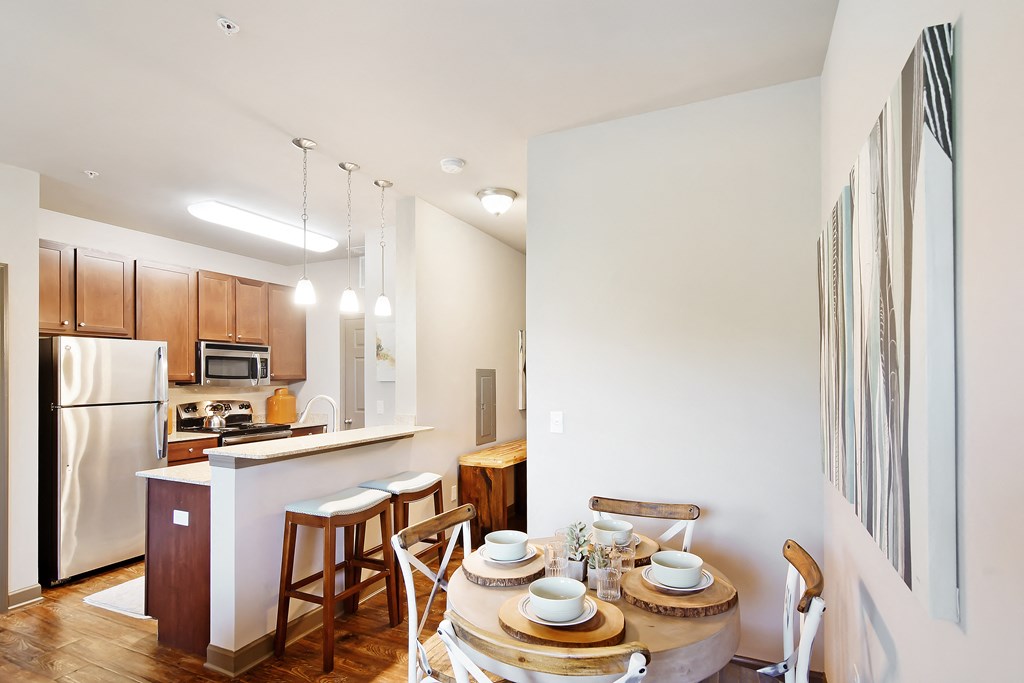 a kitchen and dining area with a wooden table and chairs and a refrigerator at Audubon Park Apartment Homes, Louisiana