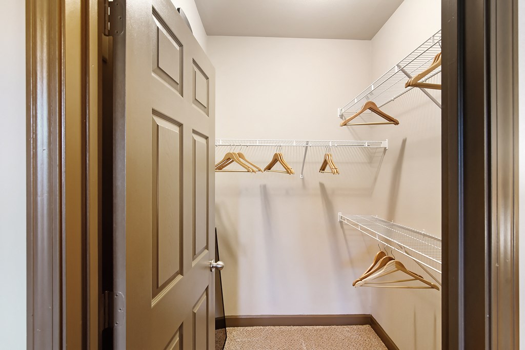 a walk in closet with white walls and hanging racks at Audubon Park Apartment Homes, Louisiana