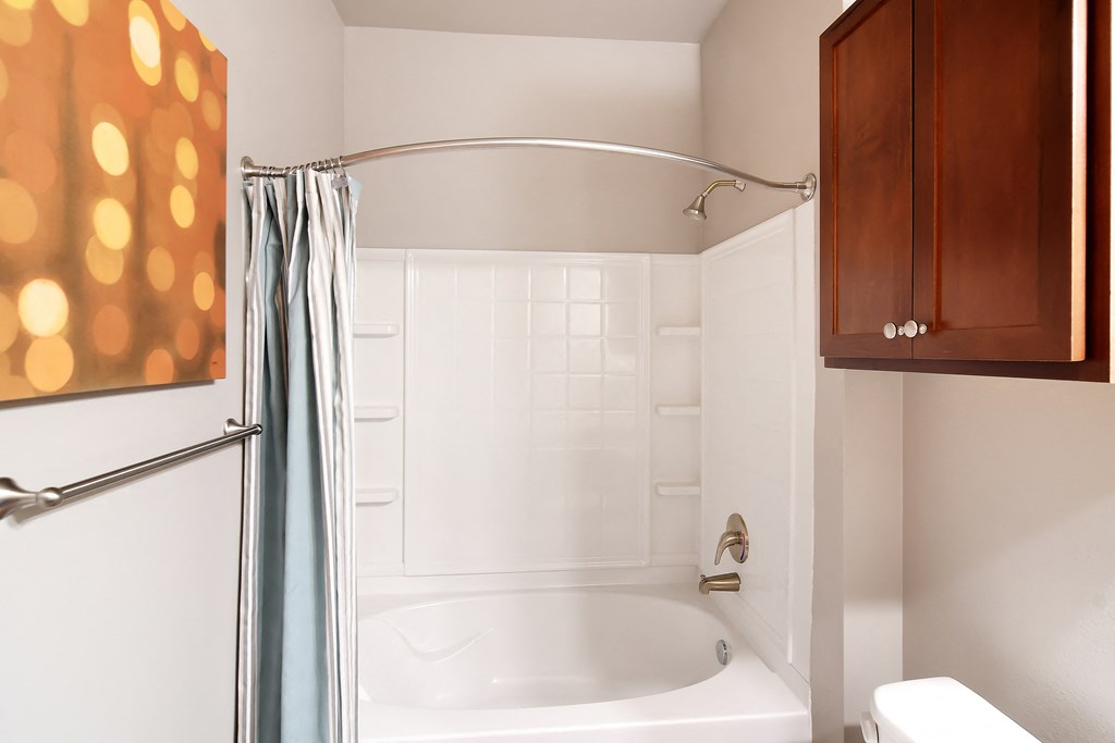 a bathroom with a white tub and a shower curtain at Audubon Park Apartment Homes, LA