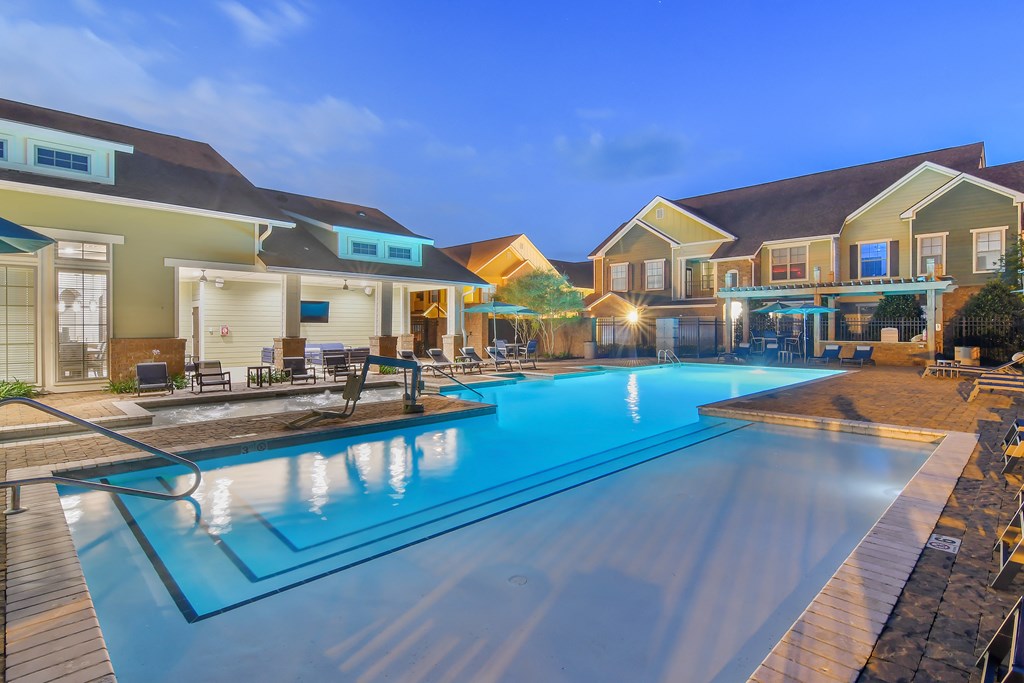 a swimming pool with houses around it at night at Audubon Park Apartment Homes, Zachary, 70791