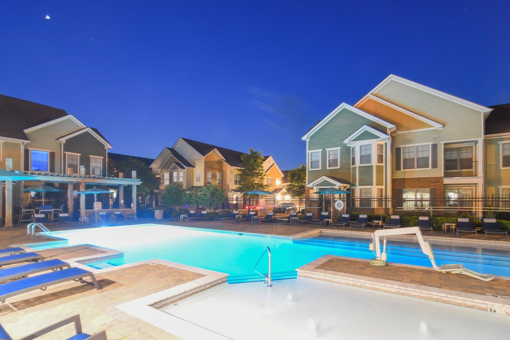 a swimming pool at night with apartments in the background at Audubon Park Apartment Homes, Zachary, 70791