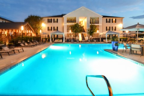 a swimming pool at night with a hotel in the background at Avalon Apartment Homes, Starkville, 39759