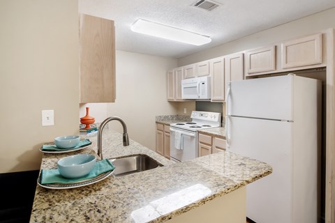 a kitchen with white appliances and a granite counter top at Avalon Apartment Homes, Starkville, 39759