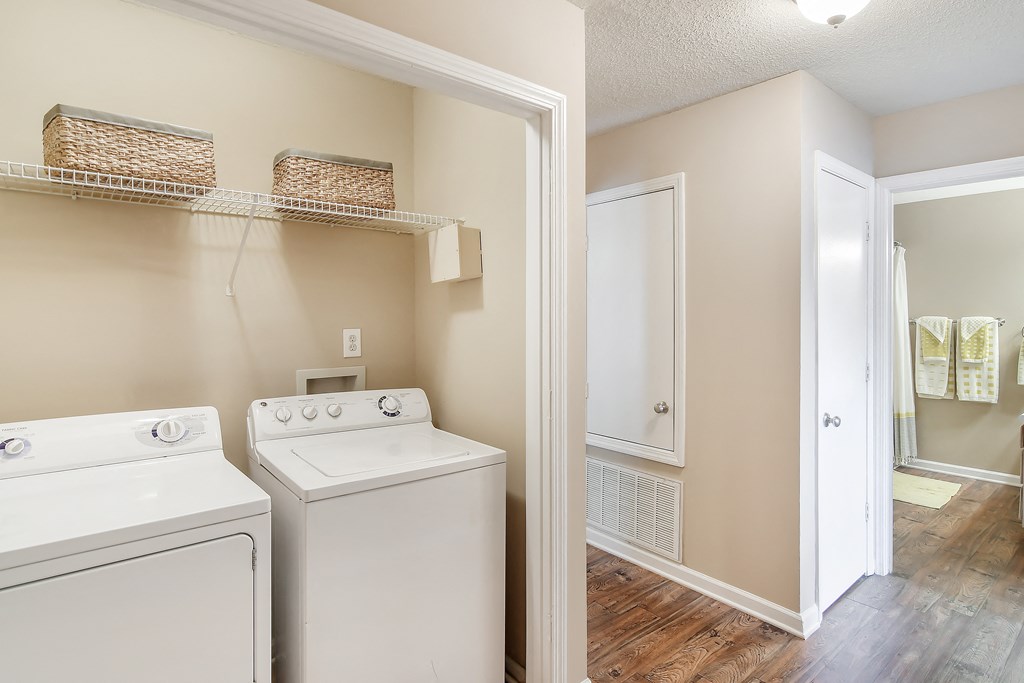a laundry room with a washer and dryer and a door to a bathroom at Avalon Apartment Homes, Mississippi