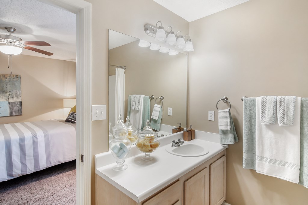 a bathroom with a sink and a mirror and a bedroom with a bed at Avalon Apartment Homes, Mississippi, 39759