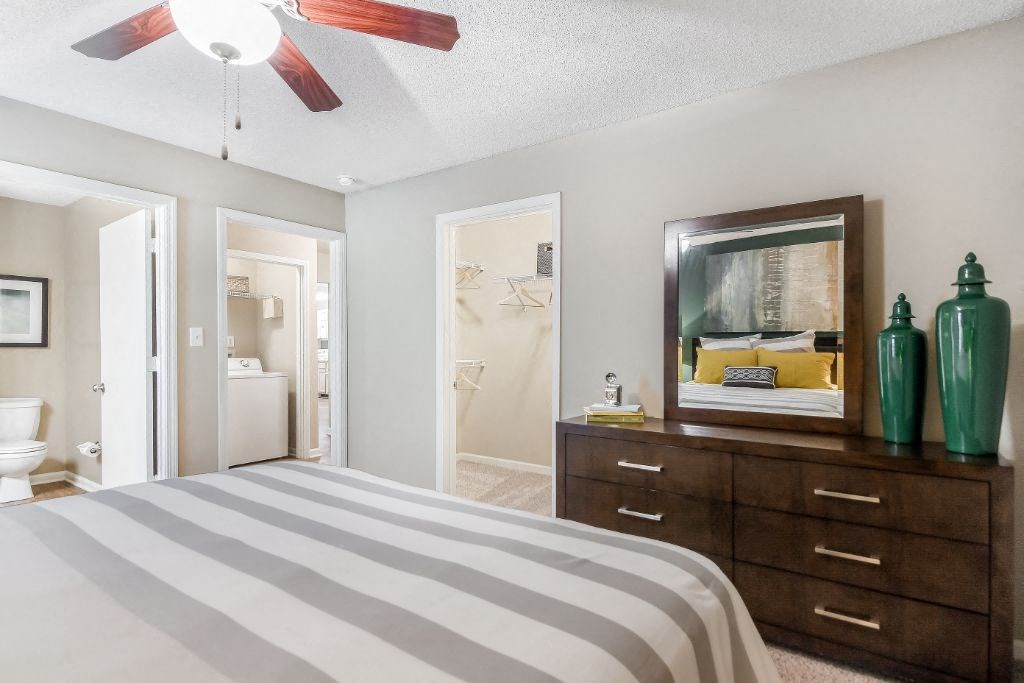 a bedroom with a large bed and a mirror at Avalon Apartment Homes, Starkville, MS, 39759