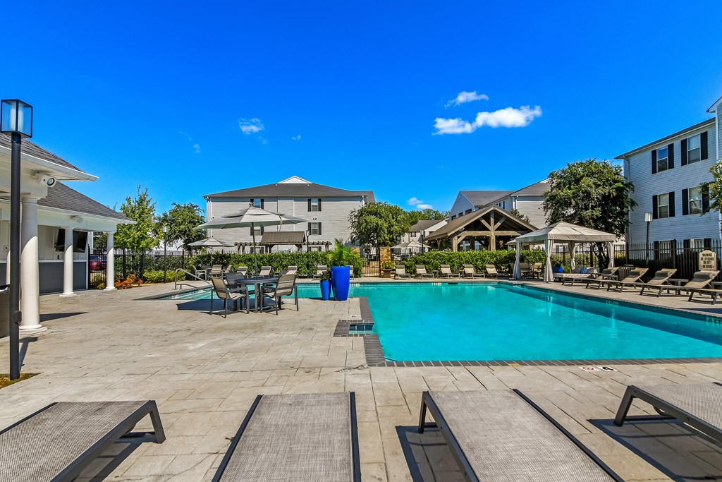 a swimming pool with tables and chairs next to a building at Avalon Apartment Homes, Starkville, MS, 39759
