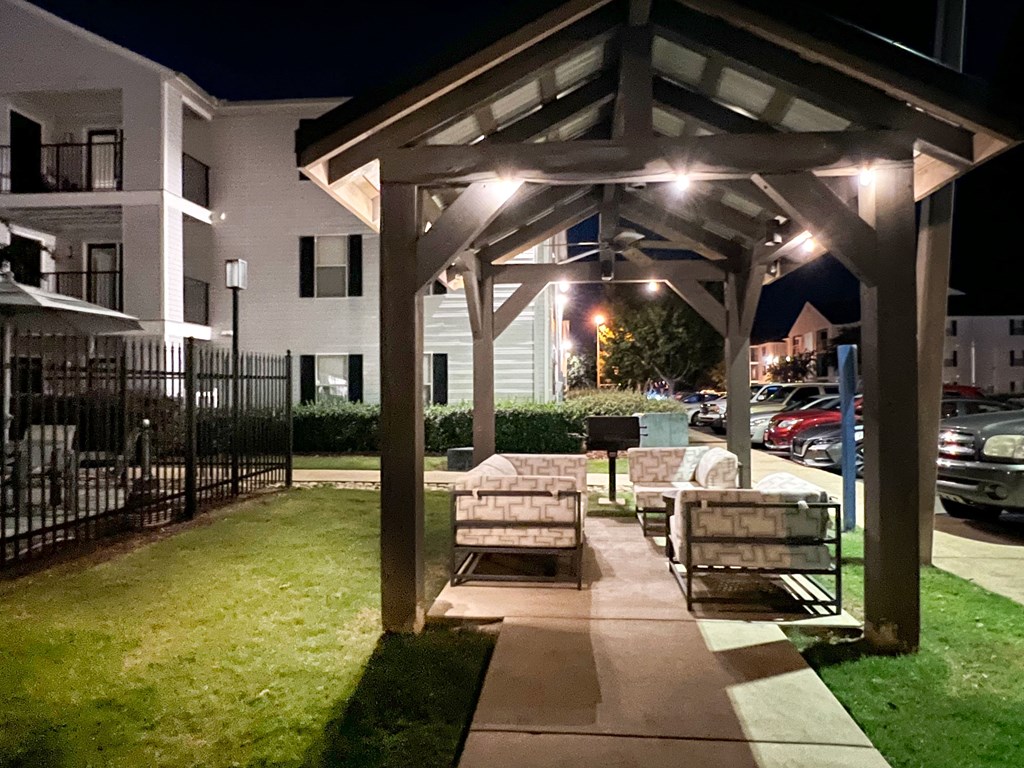 a pavilion with benches on a sidewalk at night at Avalon Apartment Homes, Starkville, 39759