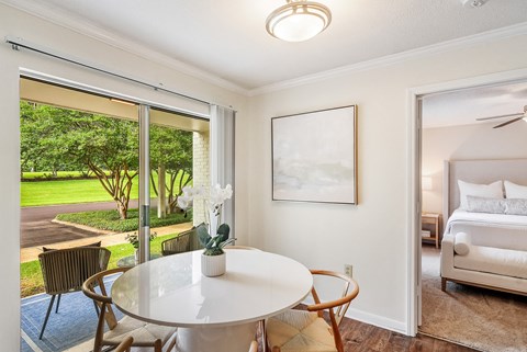 a dining area with a table and chairs and a bedroom with a bed at Cambridge Station Apartment Homes, Mississippi