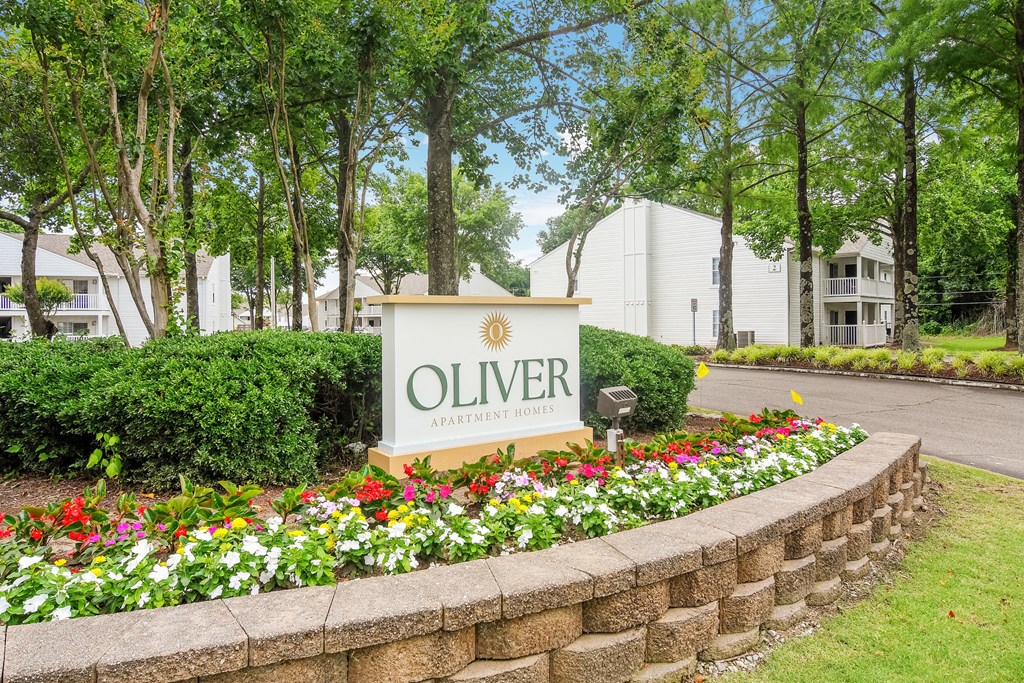 an olivier apartments sign in front of a stone wall and flowers at The Oliver Apartment Homes, Olive Branch, MS, 38654