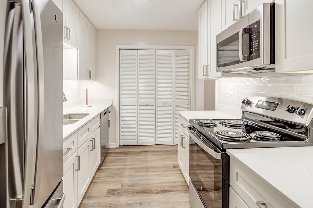 a kitchen with white cabinets and stainless steel appliances and a refrigerator at The Oliver Apartment Homes, Olive Branch, MS, 38654