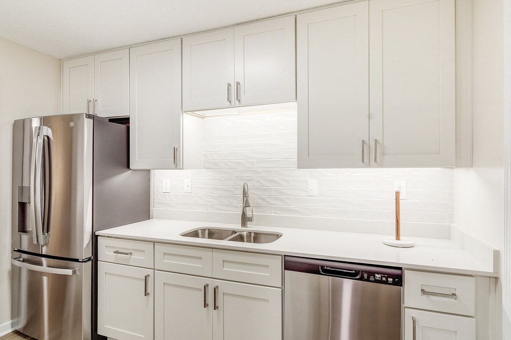 a white kitchen with stainless steel appliances and white cabinets at The Oliver Apartment Homes, Mississippi