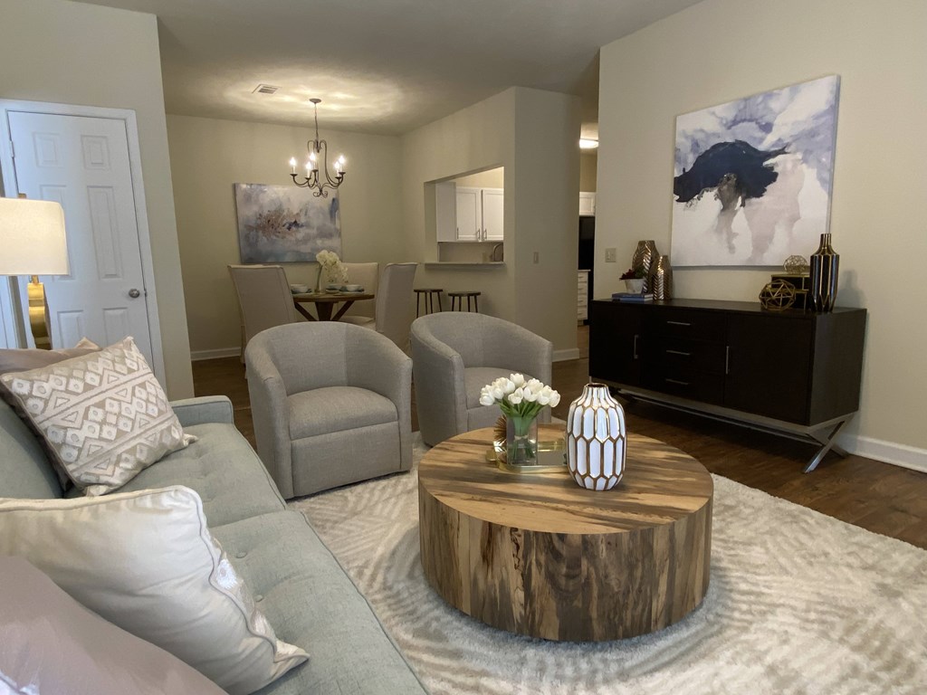 A living room with a grey couch, a wooden coffee table, and a painting on the wall.