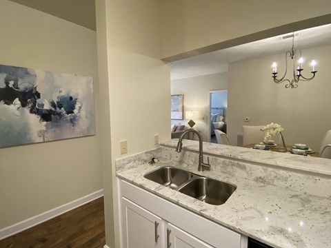 A kitchen with a marble countertop and a large painting on the wall.