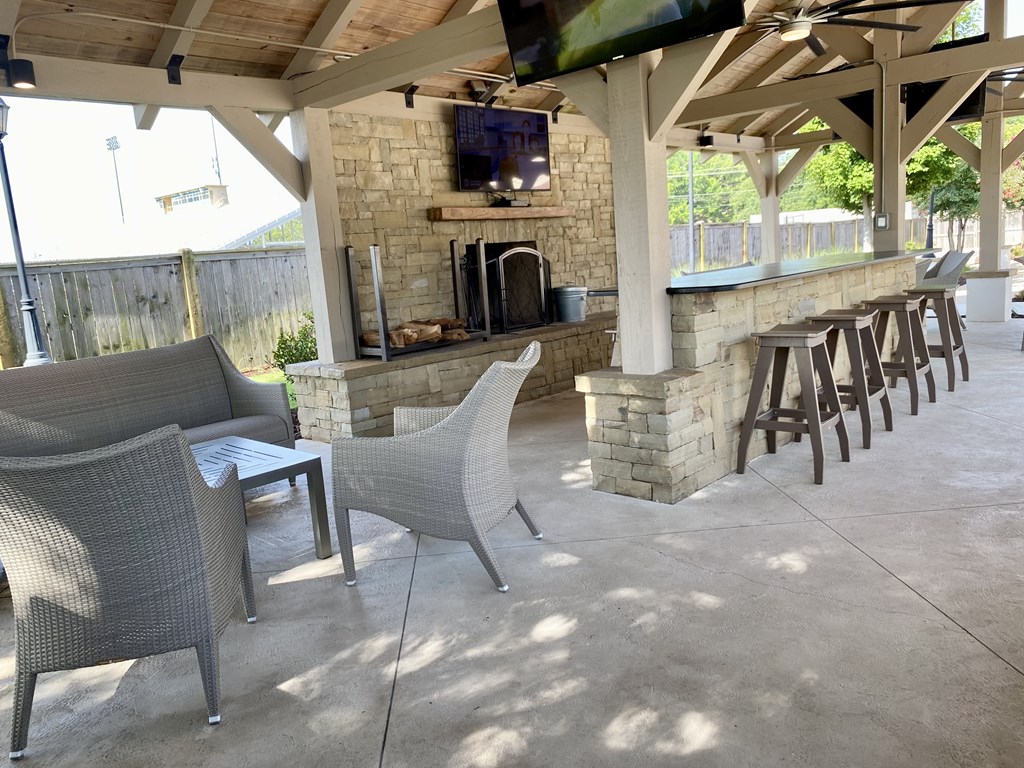 A patio with a stone fireplace and chairs.