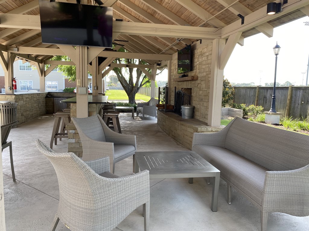 A patio with a television mounted on the ceiling and several chairs and tables.