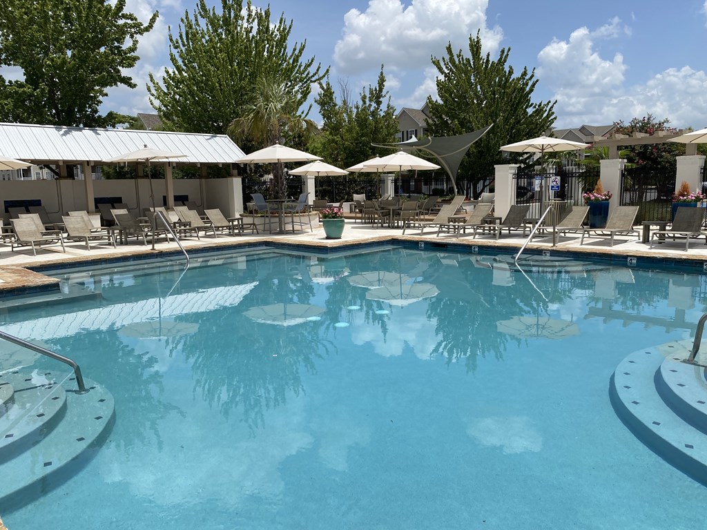 A large swimming pool surrounded by lounge chairs and umbrellas.
