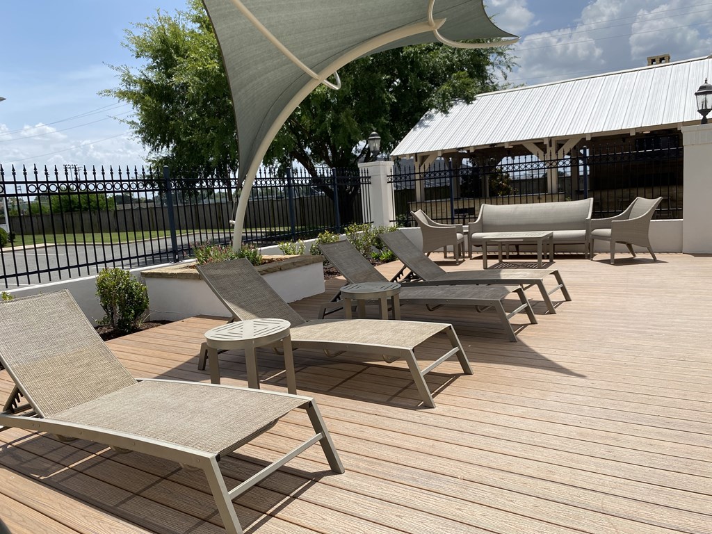 A patio with wooden decking and several chairs and tables.