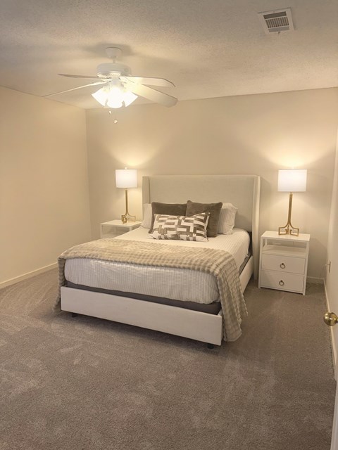 A bedroom with a bed, nightstand, and two lamps.
