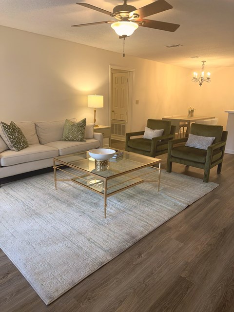 A living room with a glass coffee table and a white sofa.