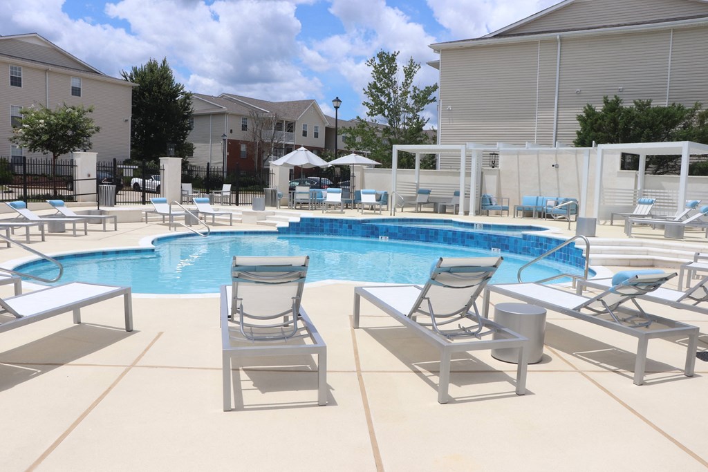 a swimming pool with lounge chairs and umbrellas at a apartment complex at Reserve at Park Place Apartments, Mississippi