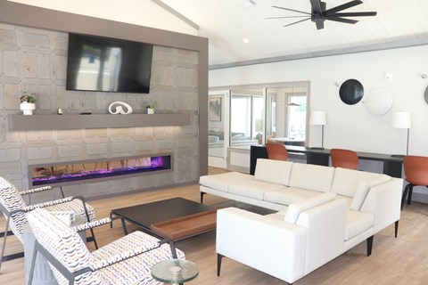 a living room with white furniture and a stone fireplace at Reserve at Park Place Apartments, Hattiesburg, MS