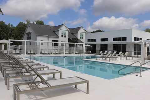 A pool with sun loungers and a building in the background.