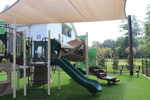 A playground with a green slide and a brown wooden structure.