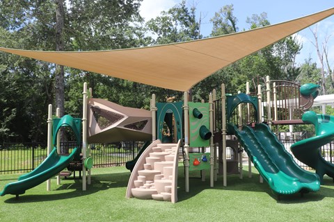 A playground with a green slide and a brown and green play structure.