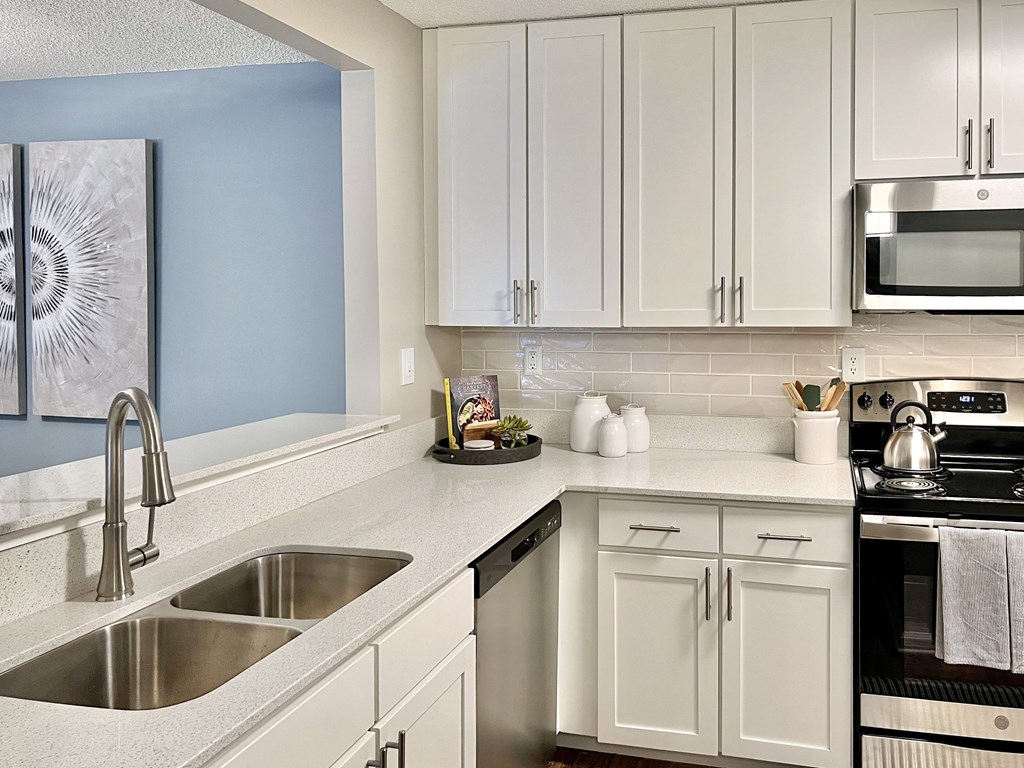 a modern kitchen with white cabinets and stainless steel appliances at Reserve at Park Place Apartments, Mississippi