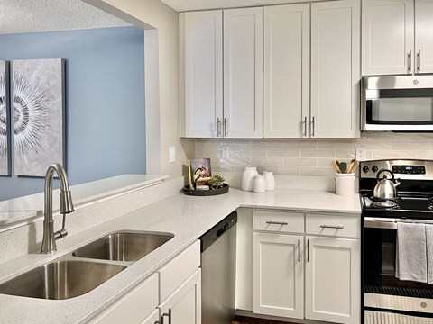 a modern kitchen with white cabinets and stainless steel appliances at Reserve at Park Place Apartments, Mississippi