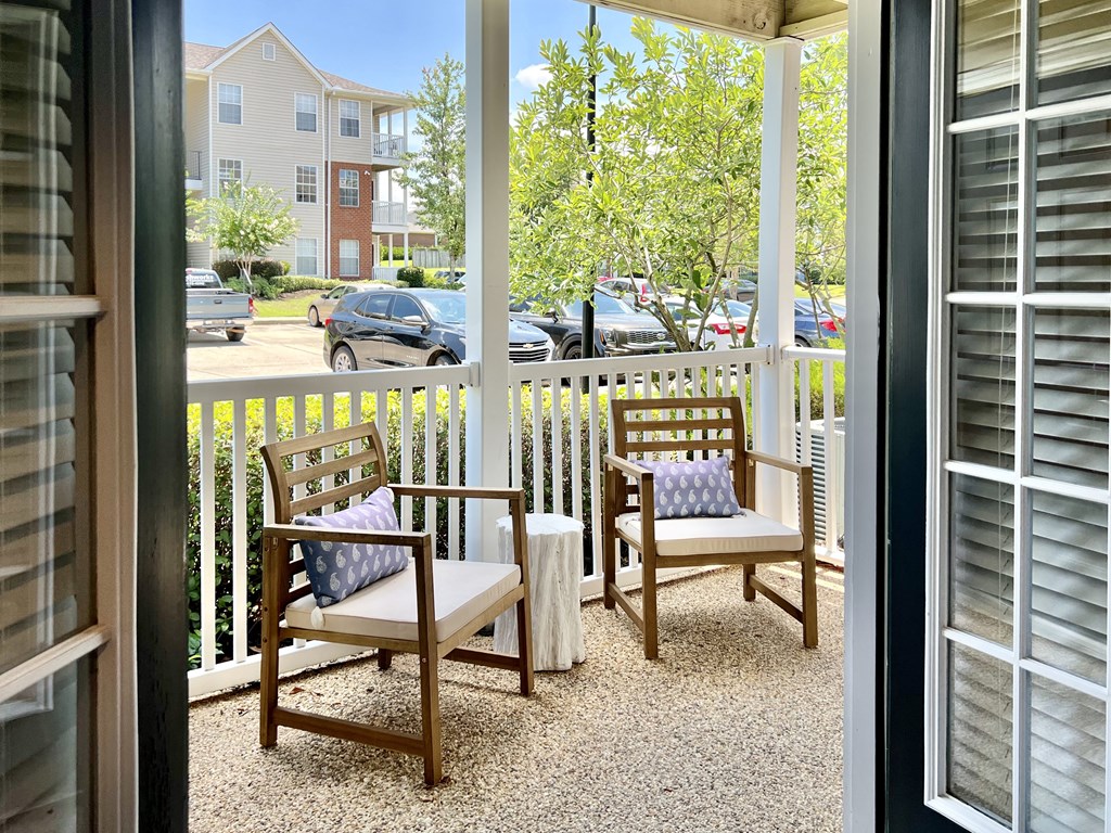 a porch with two chairs and a table and a fence at Reserve at Park Place Apartments, Hattiesburg, 39402