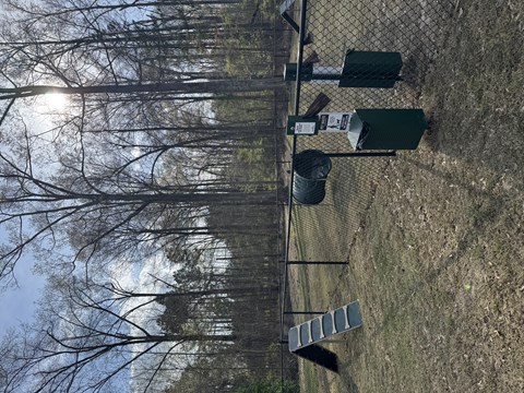 A fence with a mailbox and trash cans on top of it.