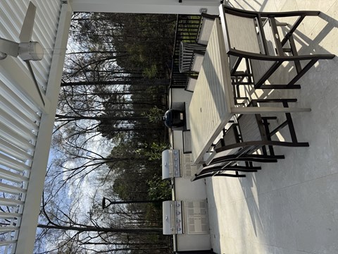 A white building with a metal staircase and a tree in the background.