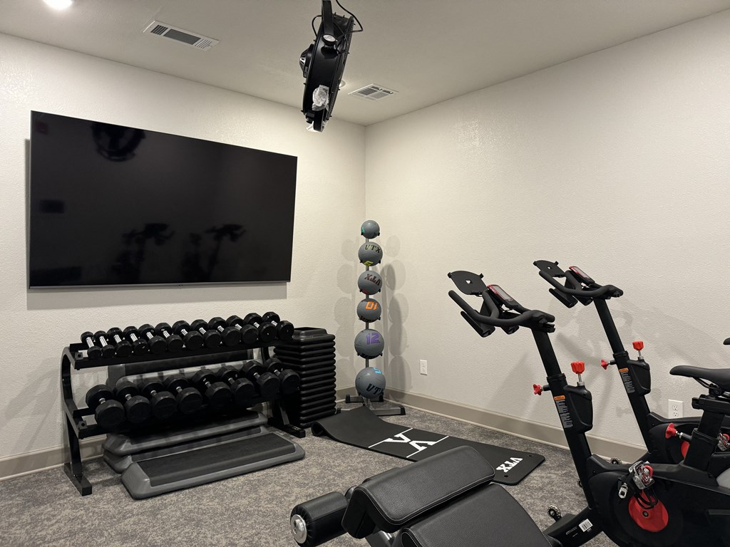 a gym with exercise equipment and a tv at Laurelwood Apartment Homes, Laurel, MS, 39440
