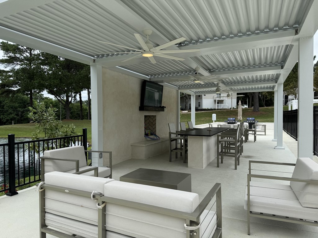 a covered patio with white furniture and a television at Laurelwood Apartment Homes, Mississippi