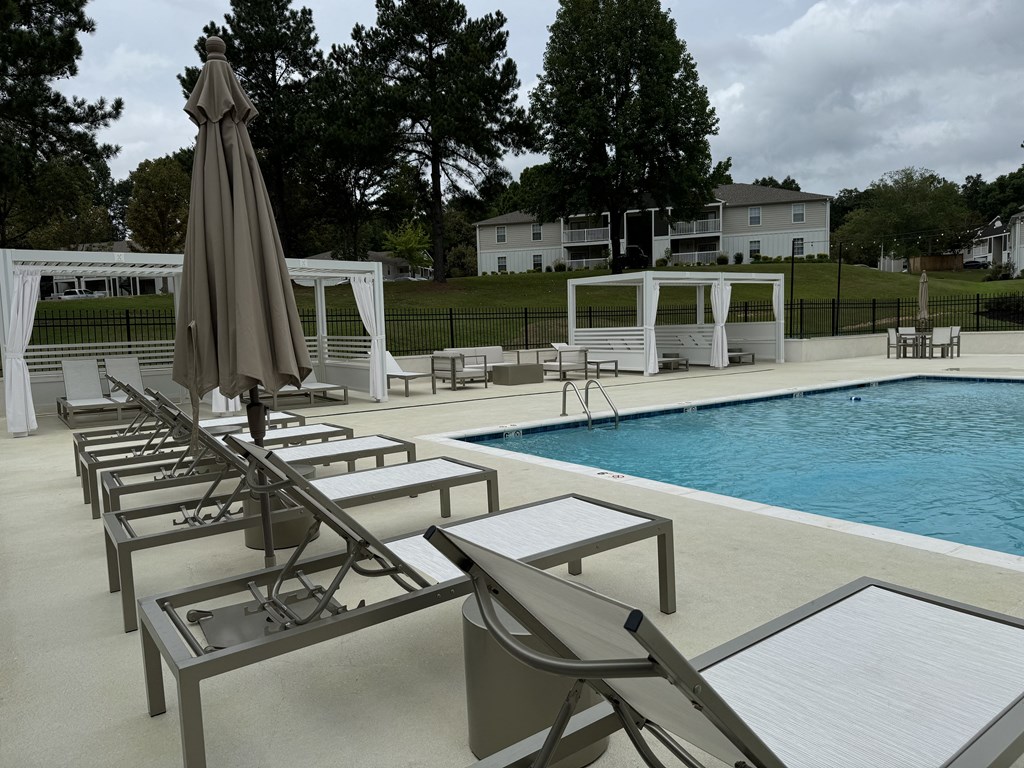 a swimming pool with chairs and an umbrella next to it at Laurelwood Apartment Homes, Mississippi, 39440