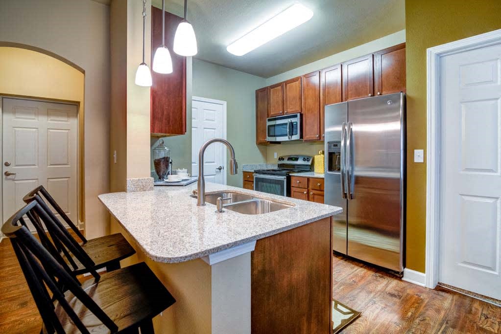 a kitchen with a granite counter top and a stainless steel refrigerator at The Retreat Apartment Homes in North Dakota 58801