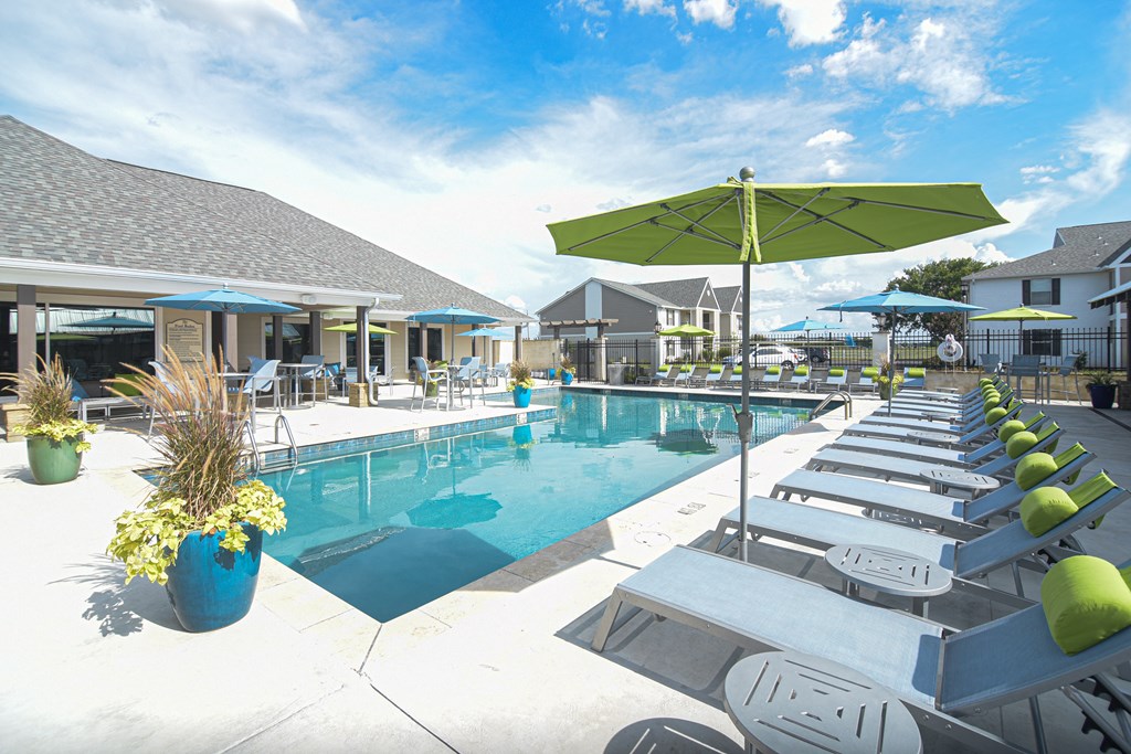 a swimming pool with lounge chairs and umbrellas at the resort at Reserve of Bossier City Apartment Homes in Bossier City, LA 