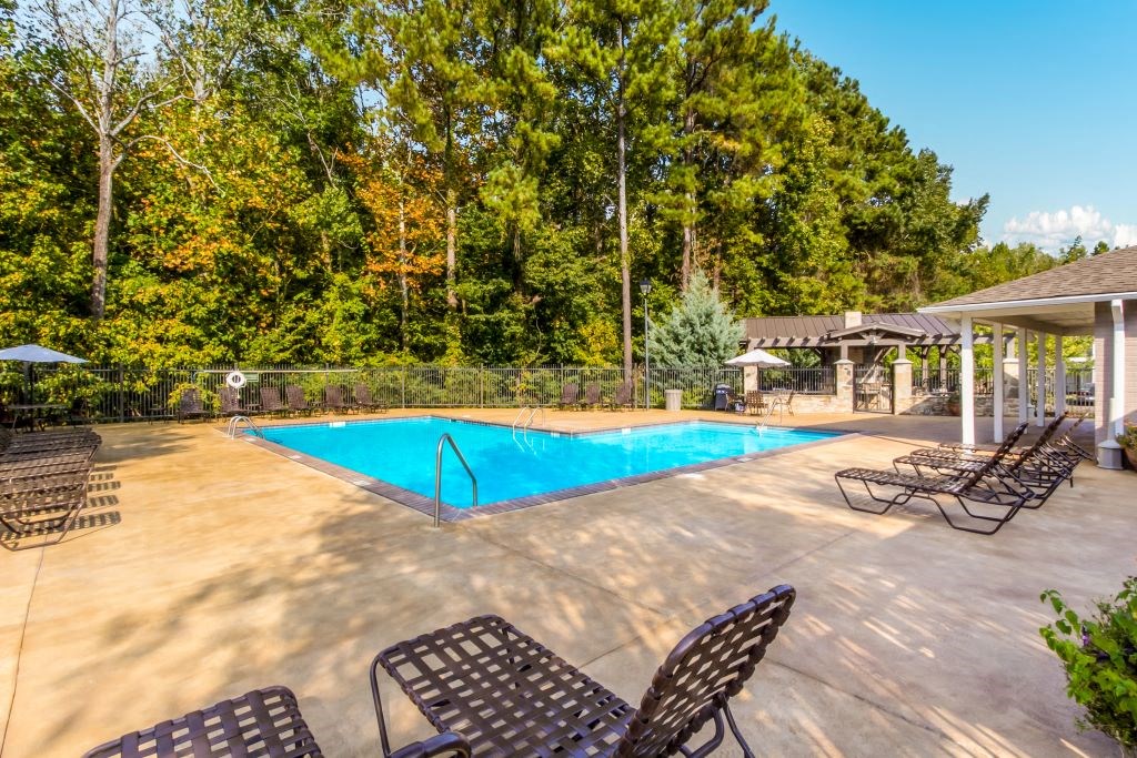 a swimming pool with chaise lounge chairs and trees in the background  at Highpointe Apartment Homes, Brandon, MS, 39042