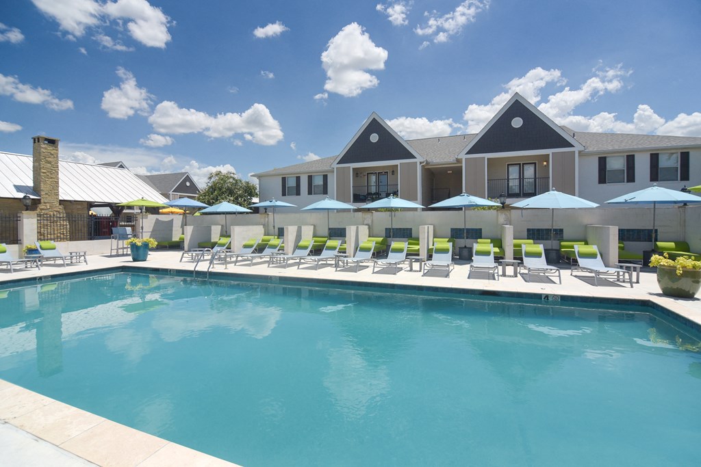 a swimming pool with lounge chairs and a building in the background at Reserve of Bossier City Apartment Homes in Louisiana 71111