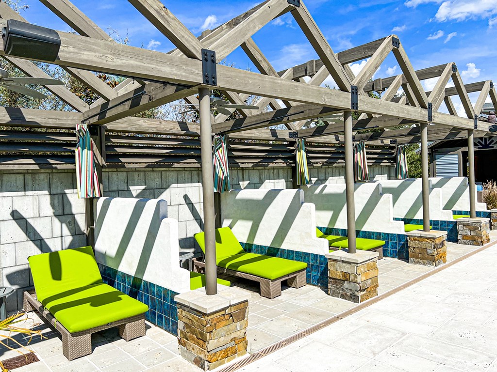 a group of green lounge chairs under a roof next to a pool at Quail Ridge Apartment Homes, Tennessee