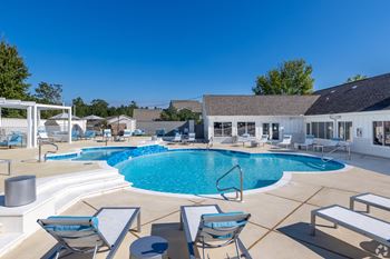 A pool with chairs and a table in the foreground at Reserve at Park Place Apartments, Mississippi