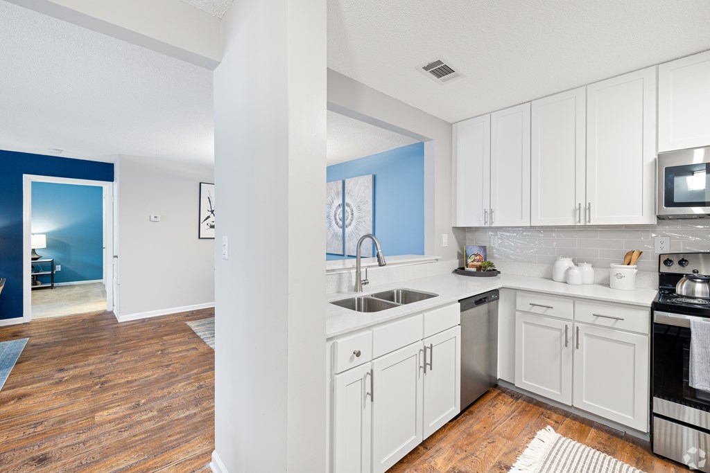 A kitchen with white cabinets and a blue accent wall. at Reserve at Park Place Apartment Homes, Hattiesburg, Mississippi